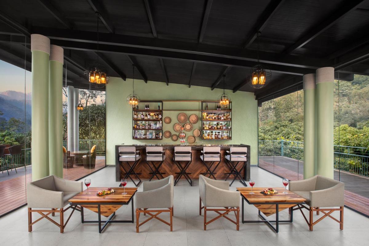 a restaurant with wooden tables and chairs and large windows at Anand Kashi by the Ganges Rishikesh - IHCL Seleqtions in Rishīkesh