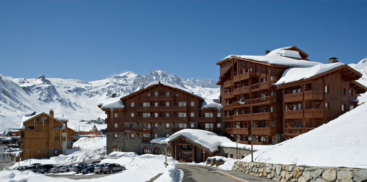 un chalet de ski sous la neige avec des voitures garées dans l'établissement Résidences Village Montana by Les Etincelles, à Tignes