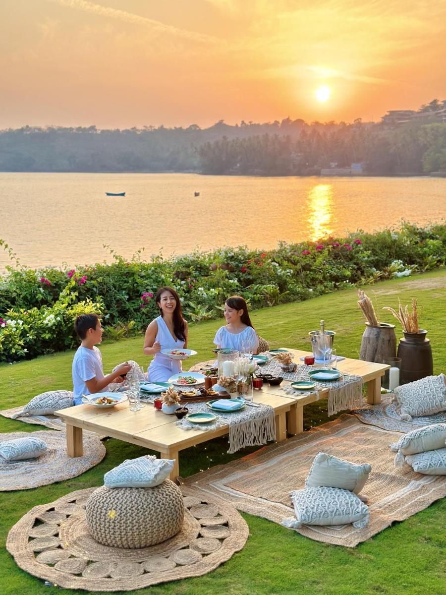 a group of people sitting at a picnic table with the sunset at Grand Hyatt Goa in Panaji a group of people sitting at a picnic table with the sunset at Grand Hyatt Goa in Panaji