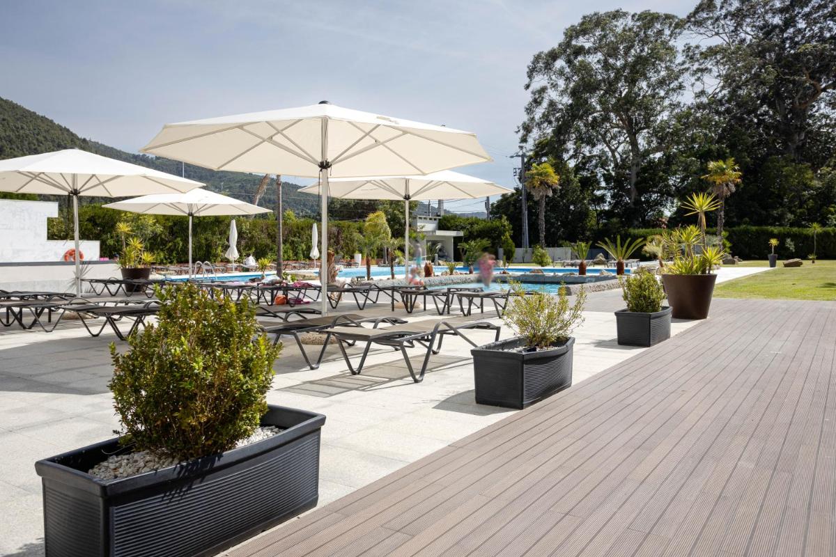 uma fileira de mesas e bancos com guarda-sóis em Hotel Porta do Sol Conference & SPA em Caminha
