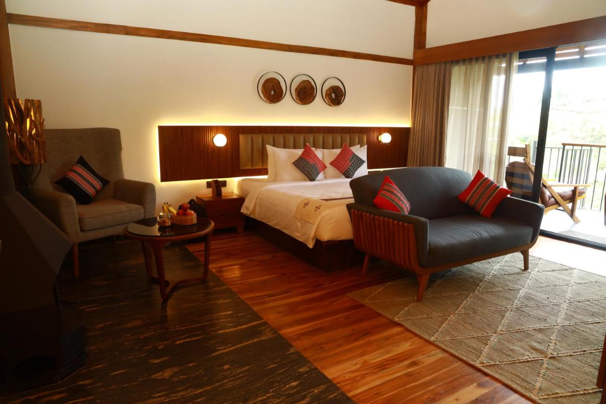 a bedroom with a bed and a couch and a chair at WelcomHeritage Ayatana Ooty in Ooty