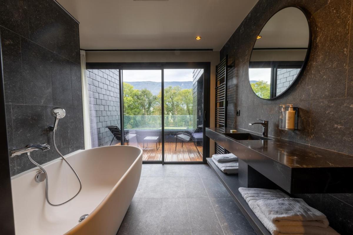 une salle de bain avec une baignoire, un lavabo et un miroir dans l'établissement Miura, à Voglans