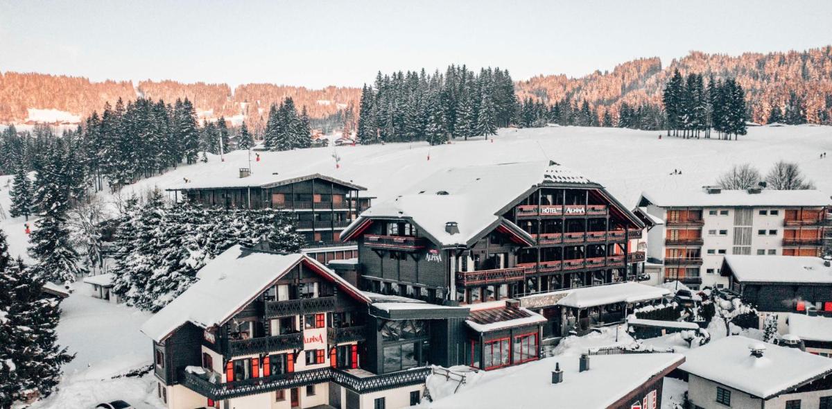 un grand bâtiment avec de la neige sur le toit dans l'établissement Hôtel Alpina & SPA - Restaurant Oxalis, aux Gets