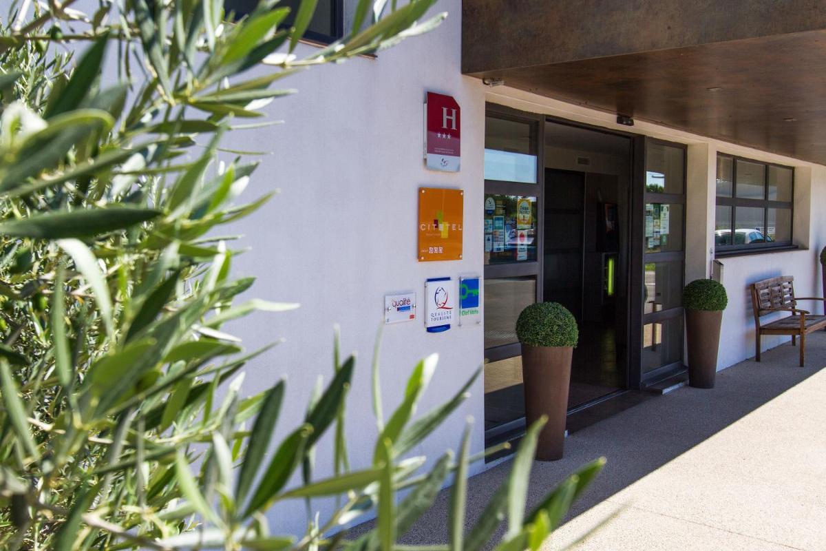 un bâtiment avec des plantes vertes devant dans l'établissement Forme-hotel & Spa Montpellier Sud-Est - Parc Expositions - Arena, à Mauguio