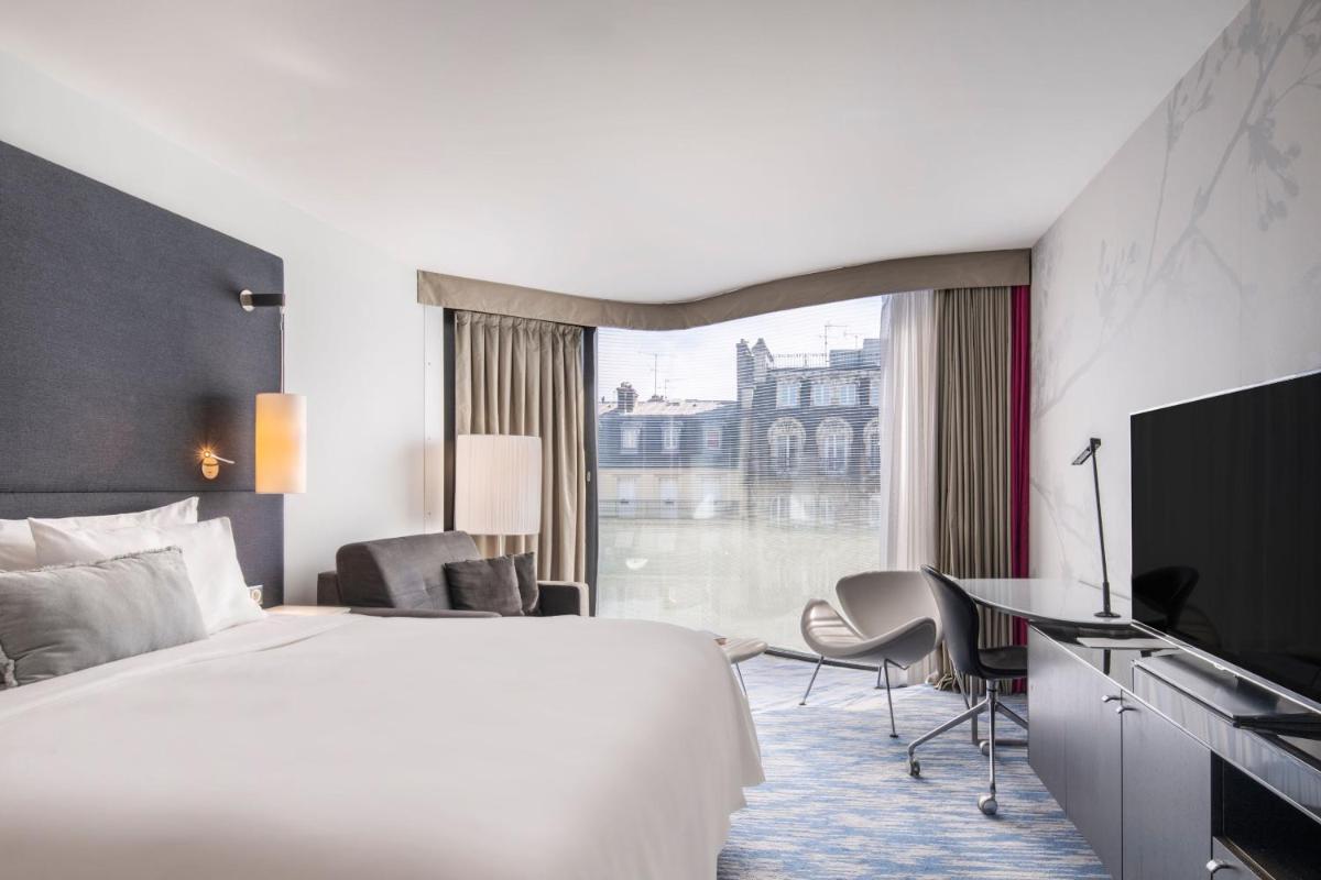 une chambre d'hôtel avec un lit, un bureau et une fenêtre dans l'établissement Renaissance Paris Arc de Triomphe Hotel, à Paris