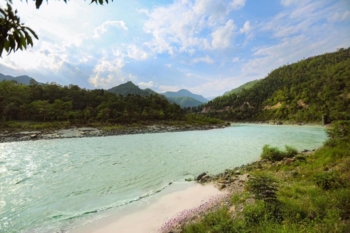 a river in the mountains with a beach at Anand Kashi by the Ganges Rishikesh - IHCL Seleqtions in Rishīkesh