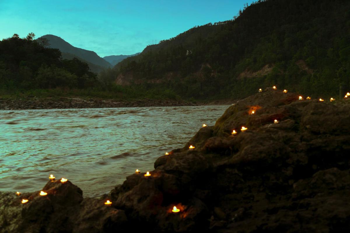 a group of lights on rocks in the water at Anand Kashi by the Ganges Rishikesh - IHCL Seleqtions in Rishīkesh