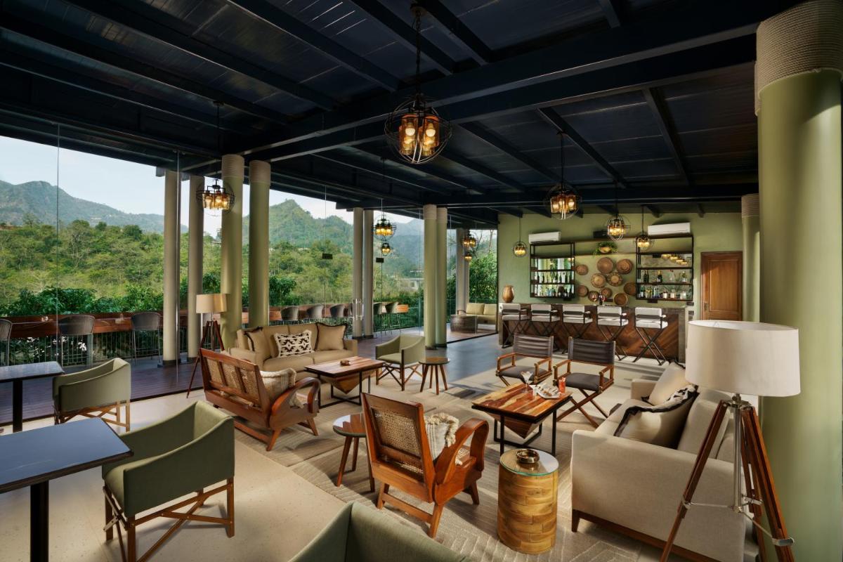 a living room with chairs and tables and windows at Anand Kashi by the Ganges Rishikesh - IHCL Seleqtions in Rishīkesh