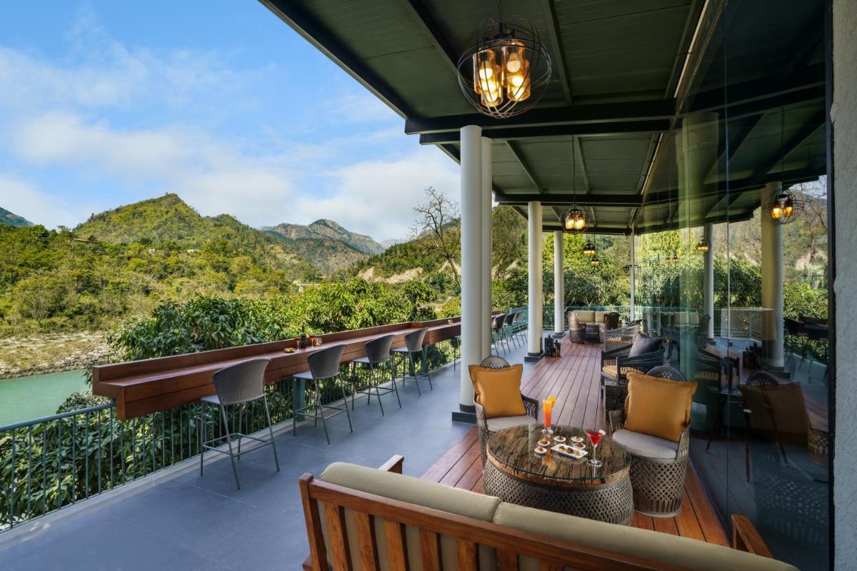 a balcony with tables and chairs and a view of the mountains at Anand Kashi by the Ganges Rishikesh - IHCL Seleqtions in Rishīkesh