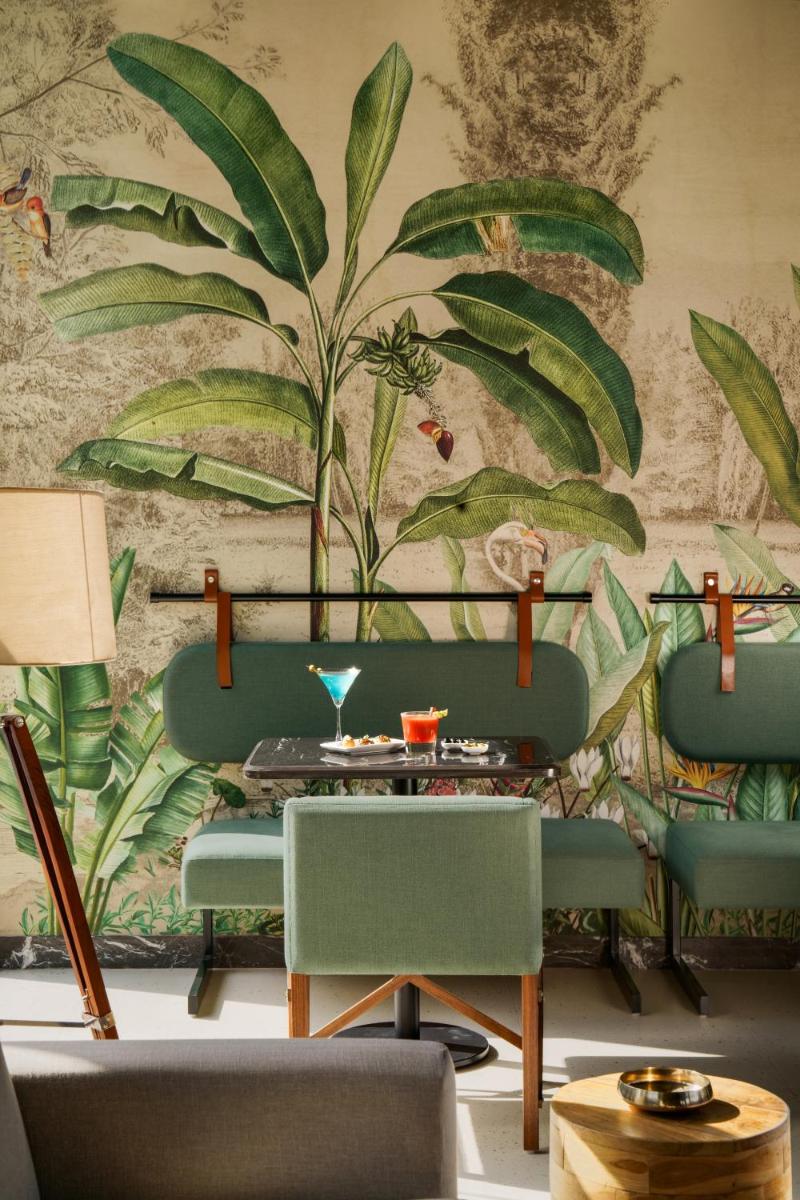 a living room with green chairs and a wall with a mural at Anand Kashi by the Ganges Rishikesh - IHCL Seleqtions in Rishīkesh