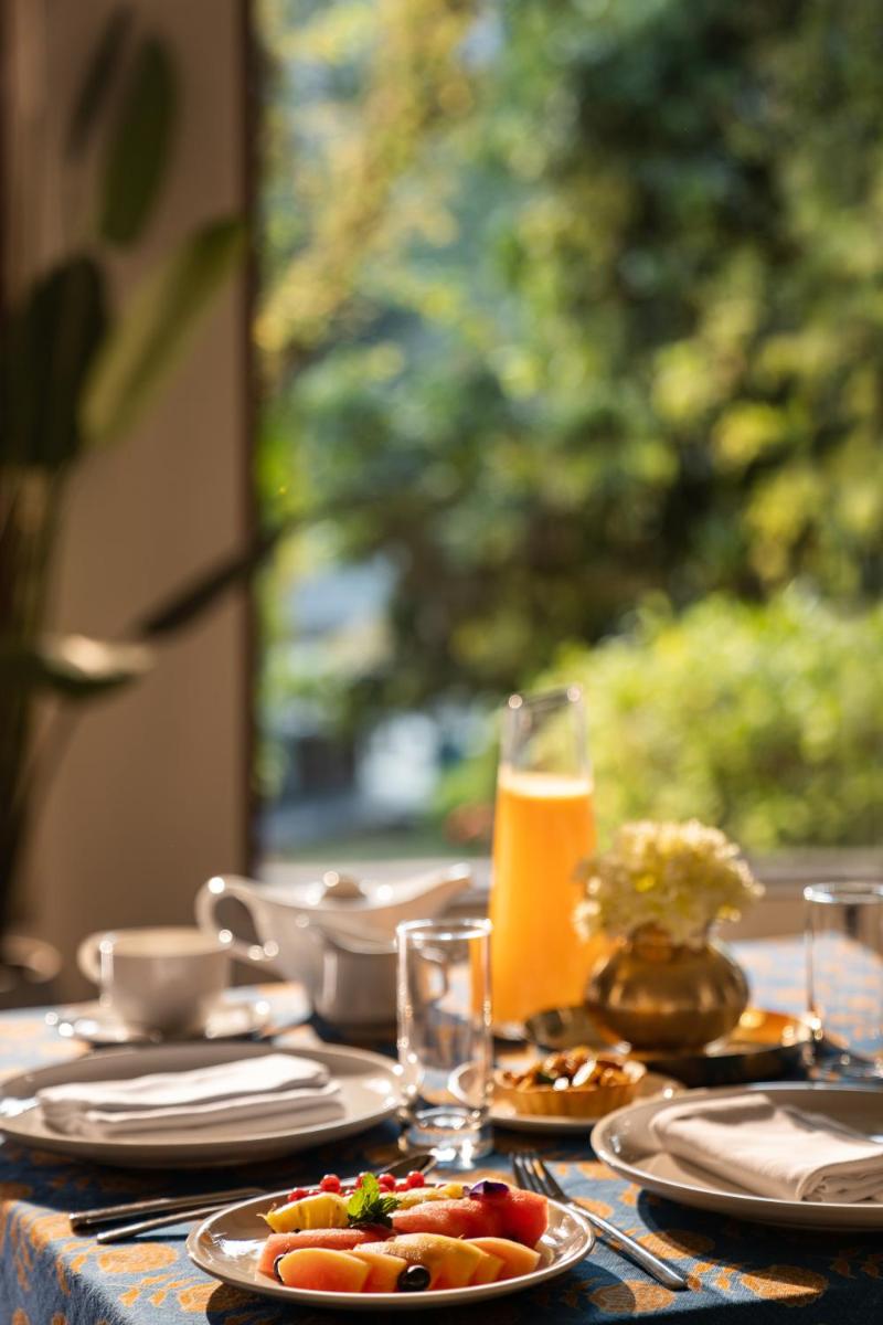 a table with plates of food and a glass of orange juice at Anand Kashi by the Ganges Rishikesh - IHCL Seleqtions in Rishīkesh