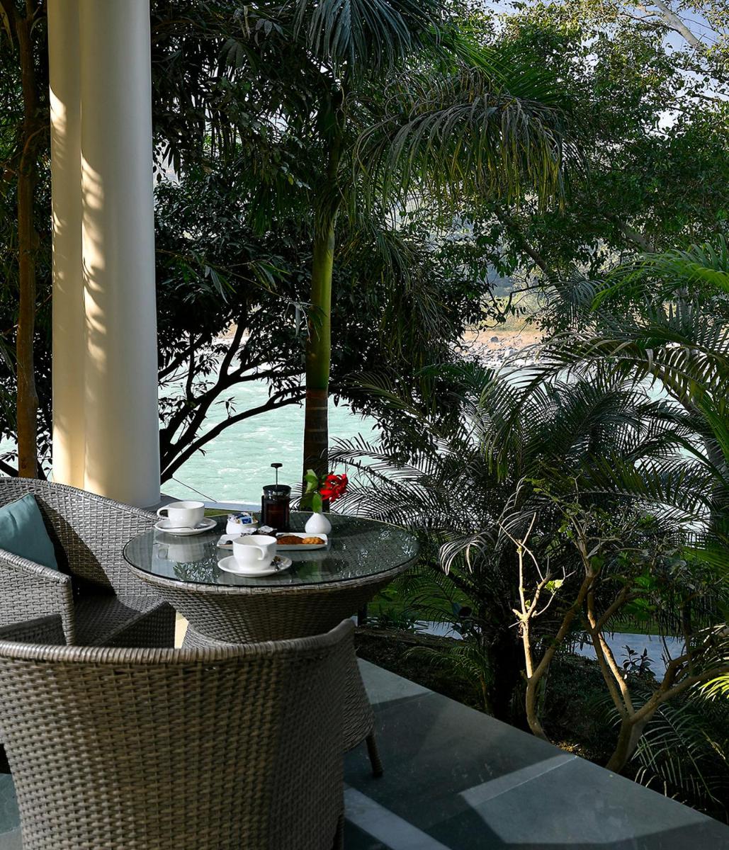 a table with a cup of coffee sitting on a balcony at Anand Kashi by the Ganges Rishikesh - IHCL Seleqtions in Rishīkesh