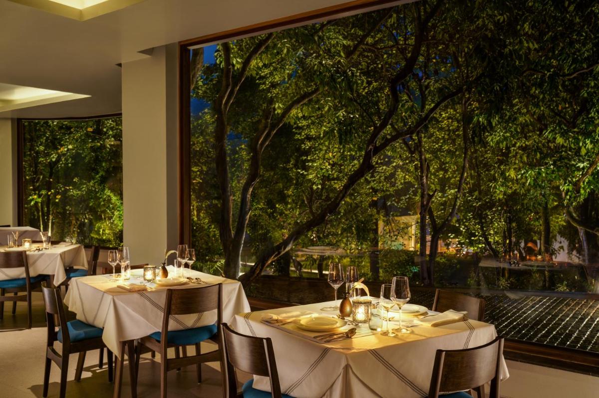 a restaurant with tables and chairs and a large window at Anand Kashi by the Ganges Rishikesh - IHCL Seleqtions in Rishīkesh