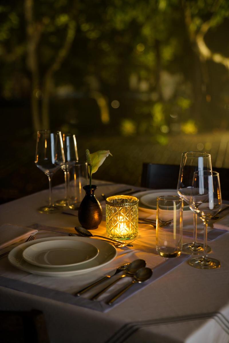 a table with plates and wine glasses on it at Anand Kashi by the Ganges Rishikesh - IHCL Seleqtions in Rishīkesh