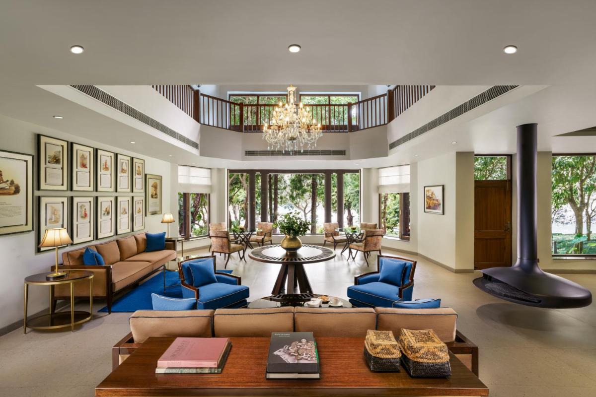 a large living room with blue chairs and a chandelier at Anand Kashi by the Ganges Rishikesh - IHCL Seleqtions in Rishīkesh