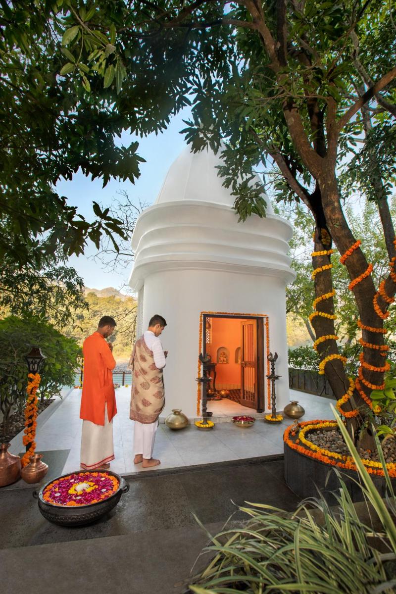 two people standing in front of a temple at Anand Kashi by the Ganges Rishikesh - IHCL Seleqtions in Rishīkesh