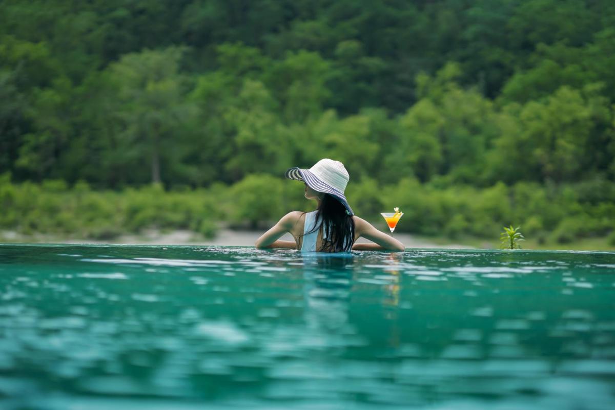 a woman wearing a hat sitting in the water at Anand Kashi by the Ganges Rishikesh - IHCL Seleqtions in Rishīkesh