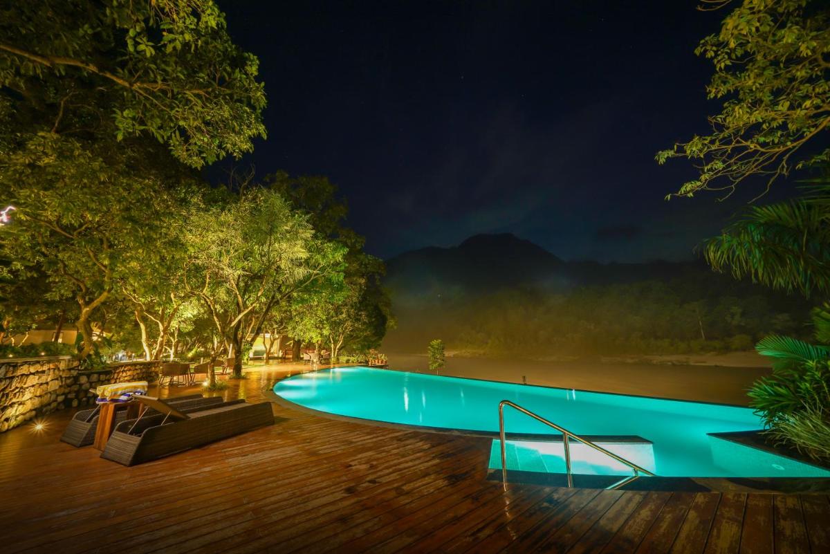 a swimming pool in the middle of a forest at night at Anand Kashi by the Ganges Rishikesh - IHCL Seleqtions in Rishīkesh
