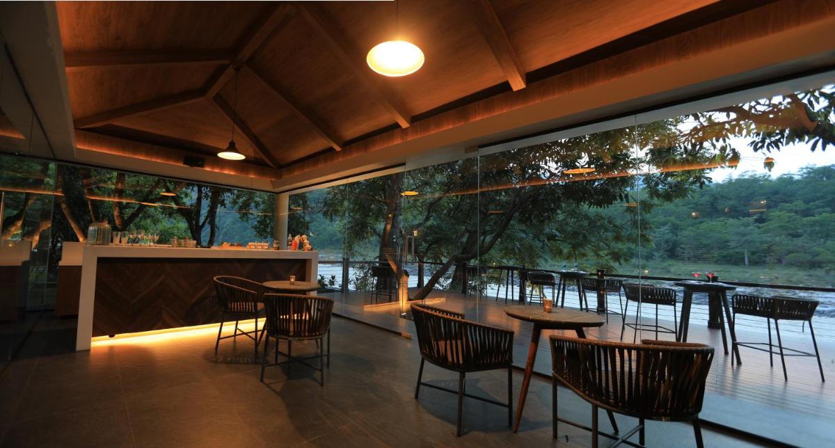 a restaurant with tables and chairs and a large window at Anand Kashi by the Ganges Rishikesh - IHCL Seleqtions in Rishīkesh