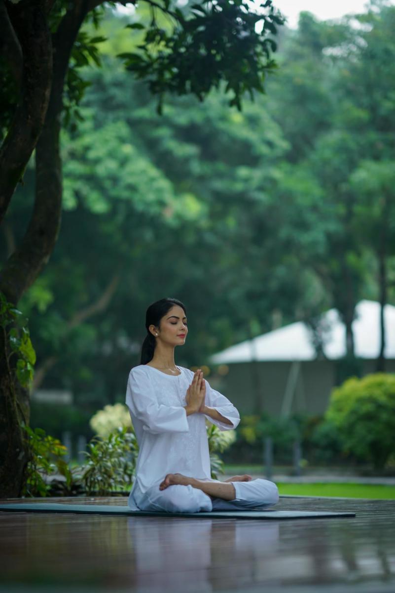 a woman in a white dress sitting on the ground at Anand Kashi by the Ganges Rishikesh - IHCL Seleqtions in Rishīkesh