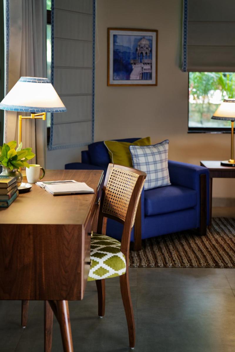 a living room with a table and a blue couch at Anand Kashi by the Ganges Rishikesh - IHCL Seleqtions in Rishīkesh