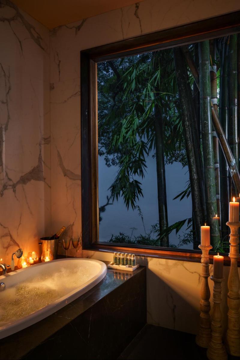 a bathroom with a tub and a window with candles at Anand Kashi by the Ganges Rishikesh - IHCL Seleqtions in Rishīkesh