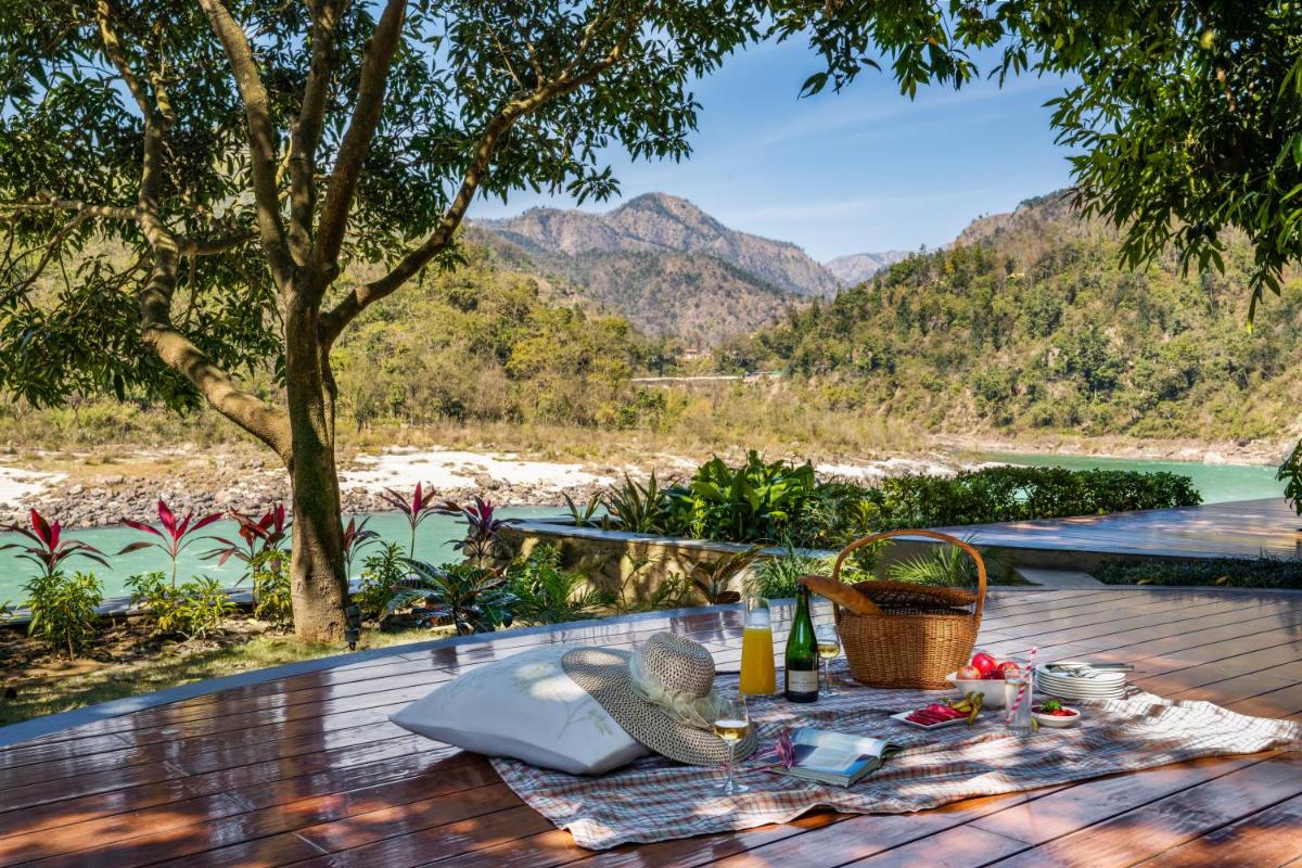 a picnic table on a deck with a view of the mountains at Anand Kashi by the Ganges Rishikesh - IHCL Seleqtions in Rishīkesh