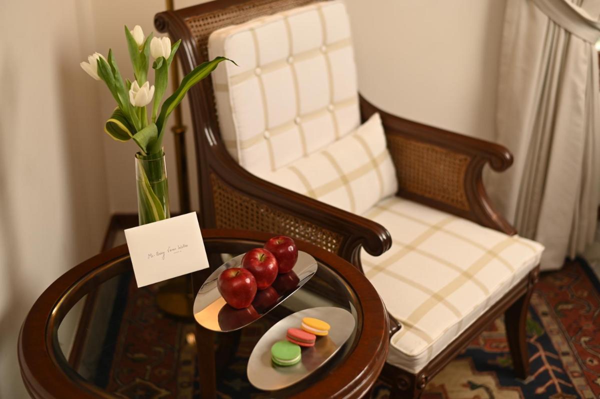 a table with a plate of fruit and a vase with flowers at The Imperial, New Delhi in New Delhi a table with a plate of fruit and a vase with flowers at The Imperial, New Delhi in New Delhi