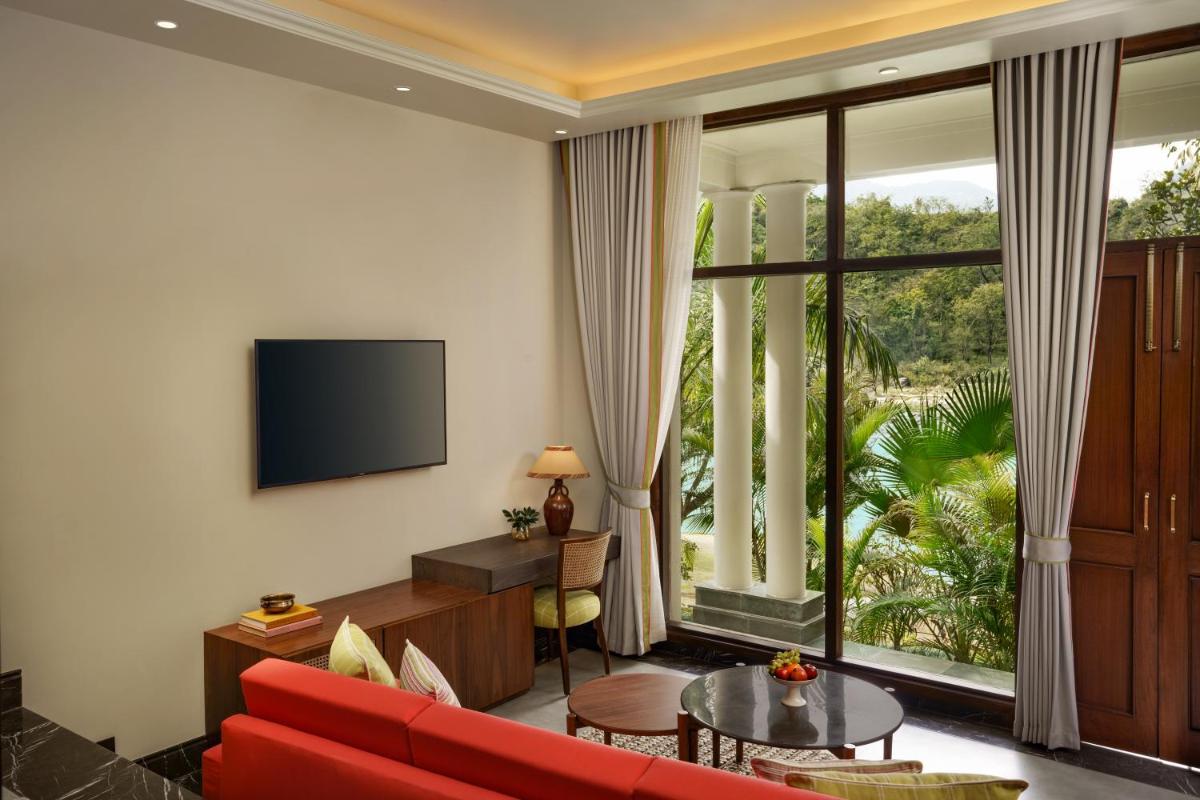 a living room with a red couch and a large window at Anand Kashi by the Ganges Rishikesh - IHCL Seleqtions in Rishīkesh