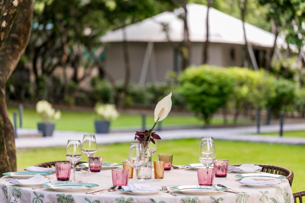a table with wine glasses and a vase on it at Anand Kashi by the Ganges Rishikesh - IHCL Seleqtions in Rishīkesh