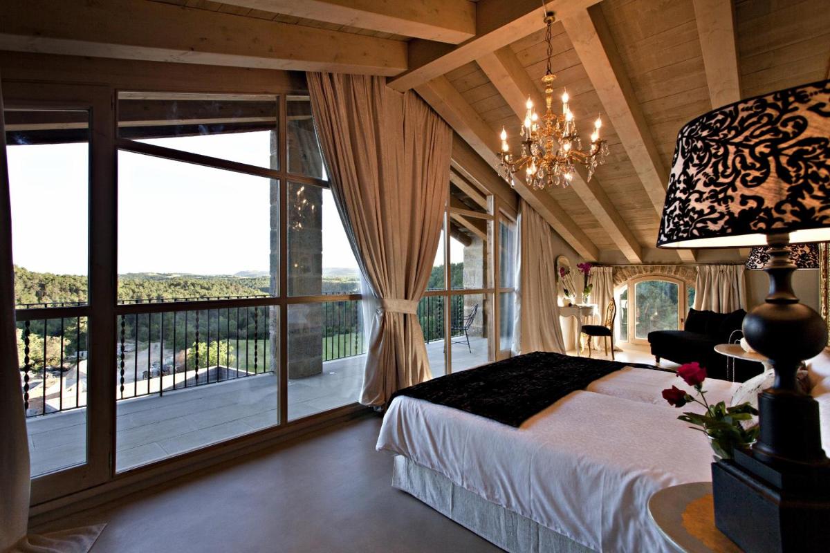 Un dormitorio con una cama y una ventana grande. en La Vella Farga Hotel, en Lladurs