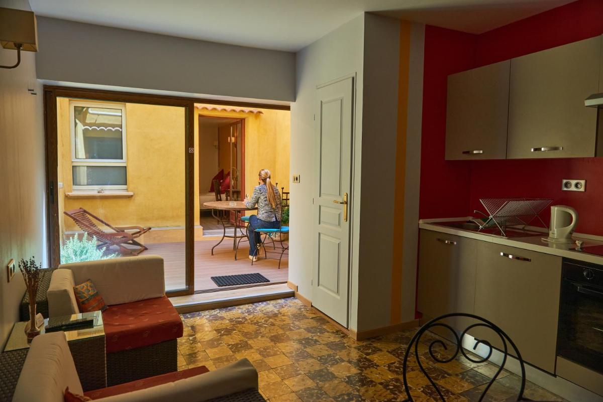 une cuisine et un salon avec une personne assise à une table dans l'établissement Les Arcades Le Lion D'or, à Buis-les-Baronnies