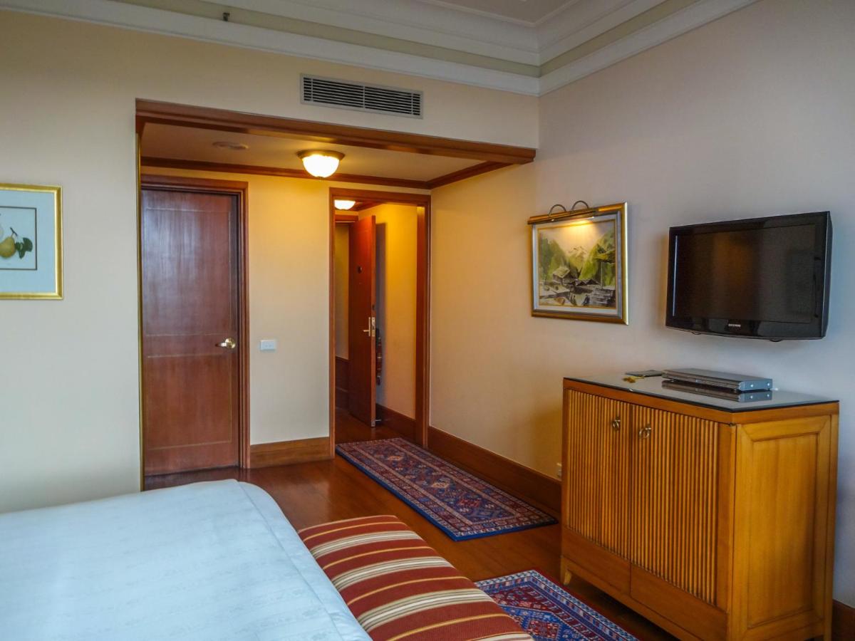 a bedroom with a bed and a flat screen tv at Wildflower Hall, An Oberoi Resort, Shimla in Shimla