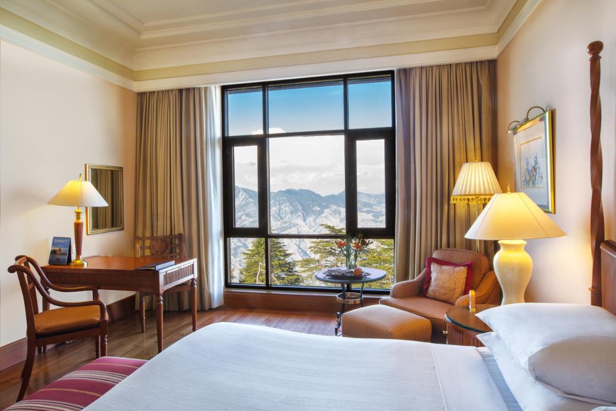 a hotel room with a bed and a desk and a window at Wildflower Hall, An Oberoi Resort, Shimla in Shimla