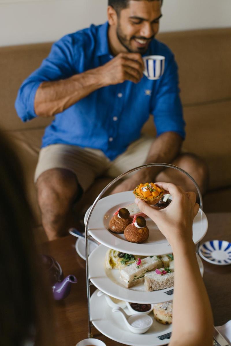 a man sitting on a couch with a plate of food at Grand Hyatt Goa in Panaji a man sitting on a couch with a plate of food at Grand Hyatt Goa in Panaji