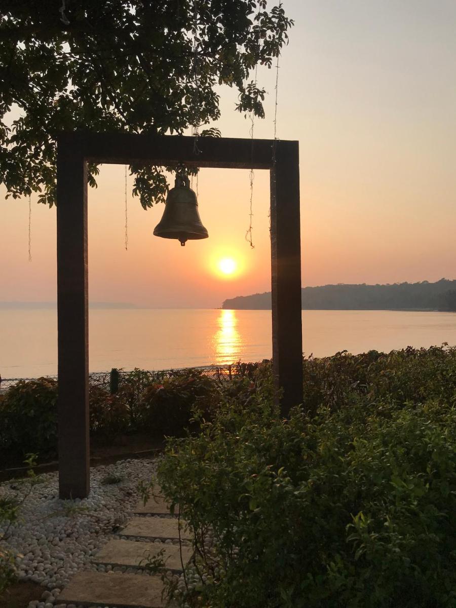 a bell hanging from a tree with the sunset in the background at Grand Hyatt Goa in Panaji a bell hanging from a tree with the sunset in the background at Grand Hyatt Goa in Panaji