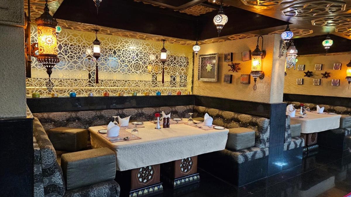 a restaurant with two tables and a tile wall at Sterlings Mac Hotel in Bengaluru