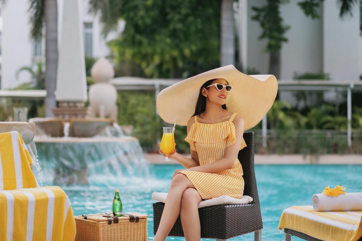 a woman in a straw hat sitting in a chair with a drink at The Imperial, New Delhi in New Delhi a woman in a straw hat sitting in a chair with a drink at The Imperial, New Delhi in New Delhi