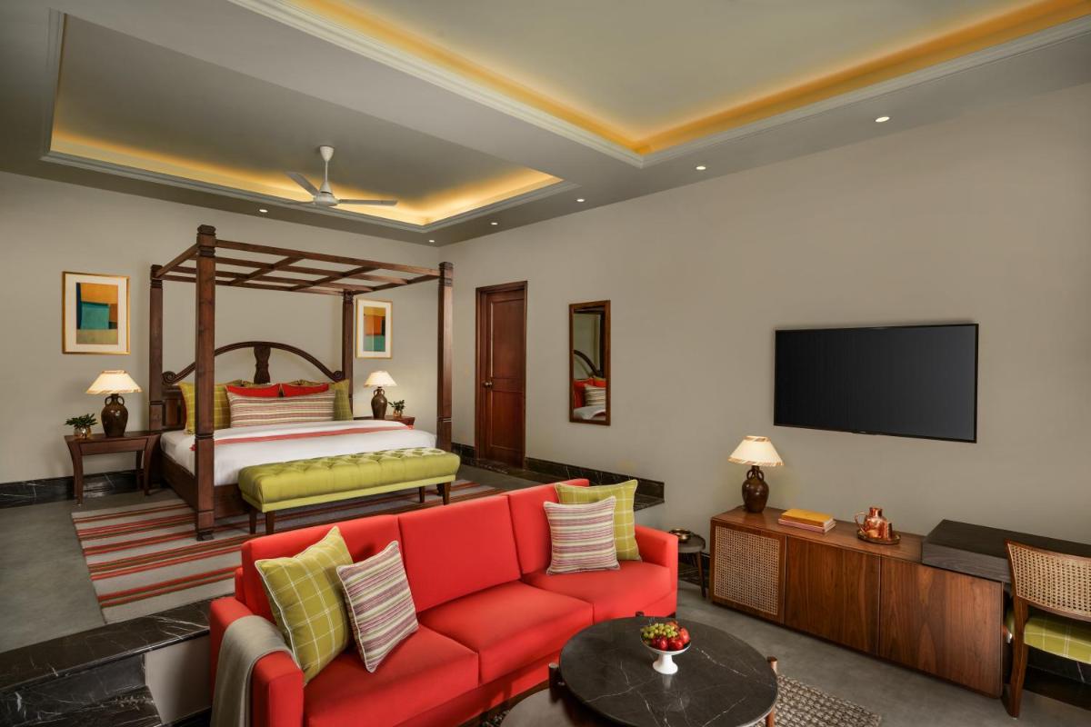 a living room with a red couch and a bed at Anand Kashi by the Ganges Rishikesh - IHCL Seleqtions in Rishīkesh