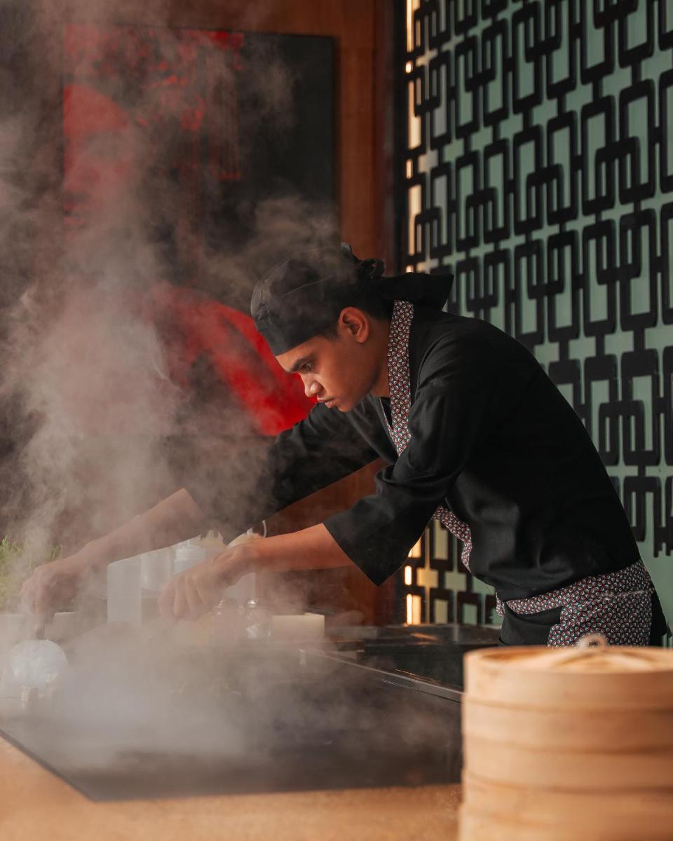 a man cooking food on a table with smoke at Hyatt Pune in Pune