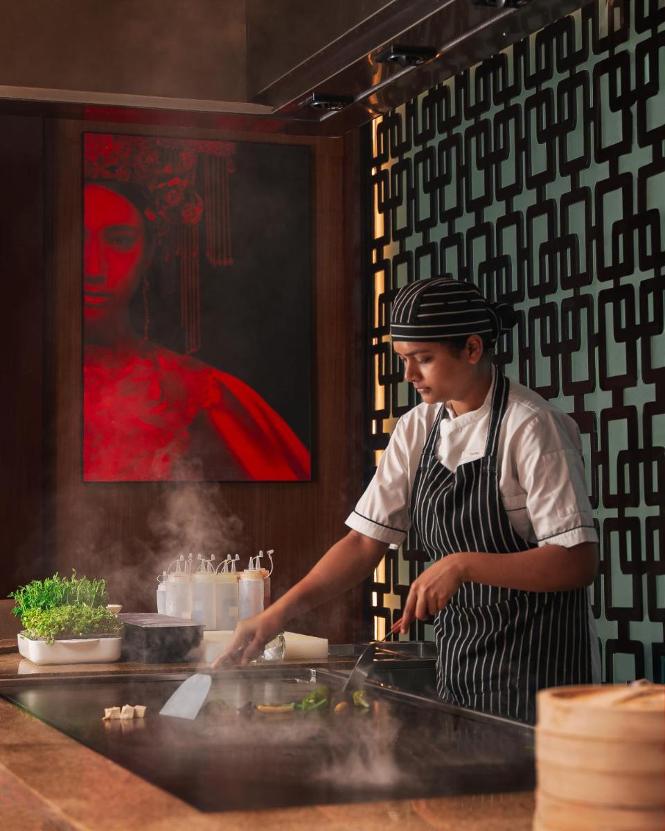 a chef preparing food in a restaurant kitchen at Hyatt Pune in Pune
