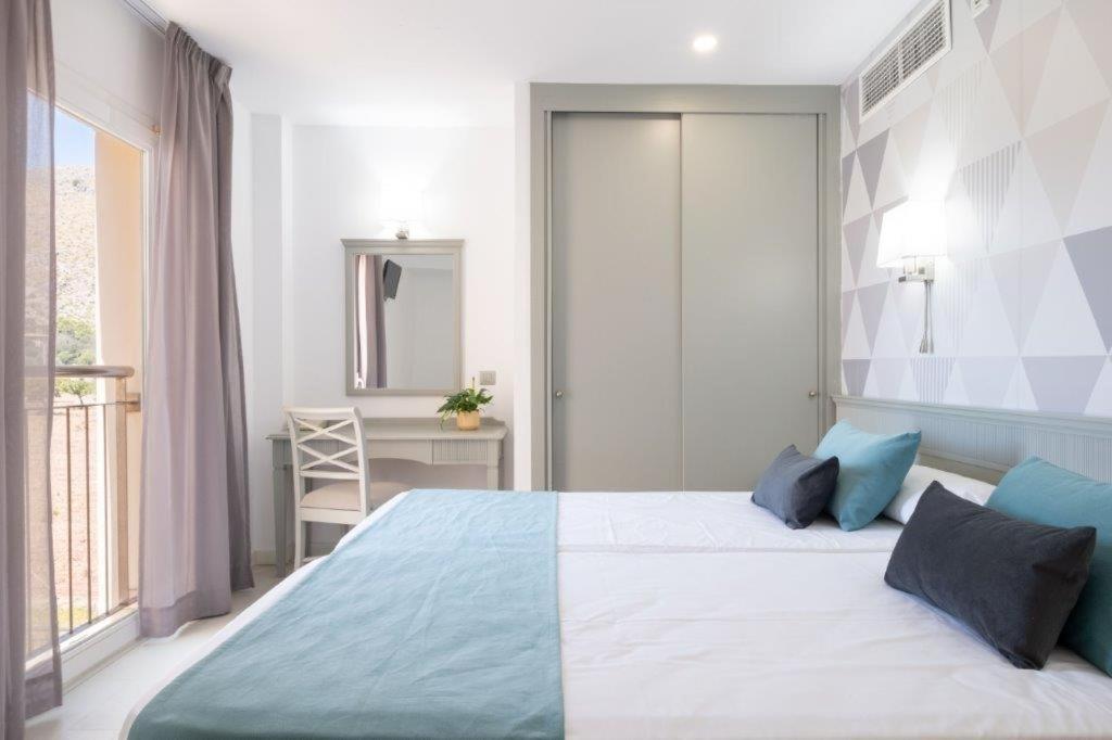 Un dormitorio con una cama grande con almohadas azules. en Aparthotel Duva & Spa, en Puerto Pollensa 71 fotos más