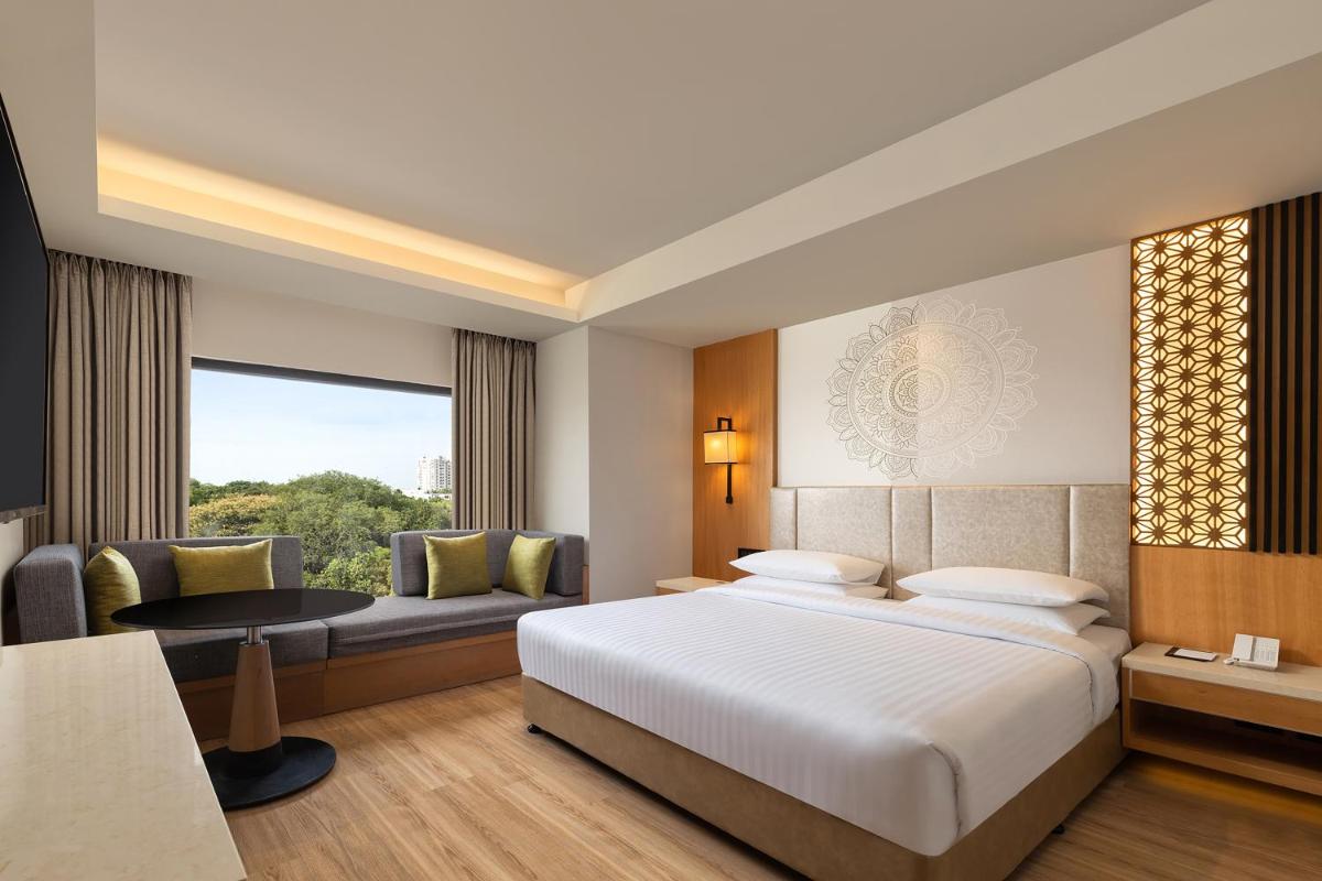 a hotel room with a bed and a couch at Courtyard by Marriott Tiruchirappalli in Tiruchchirāppalli