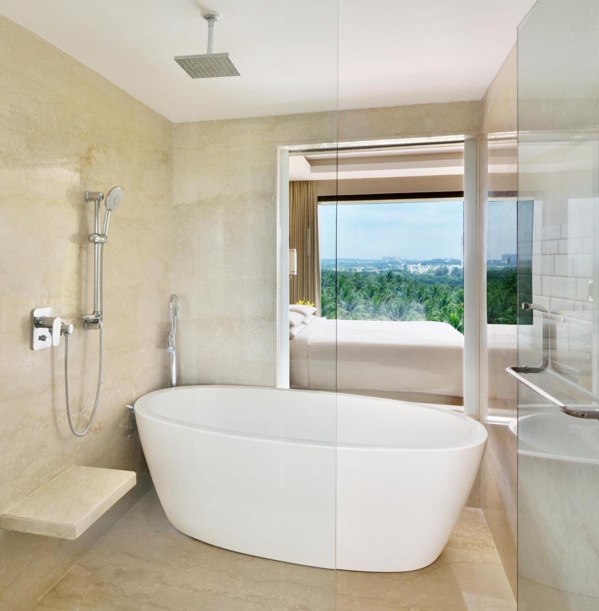 a bathroom with a tub and a glass shower at Courtyard by Marriott Bengaluru Hebbal in Bengaluru
