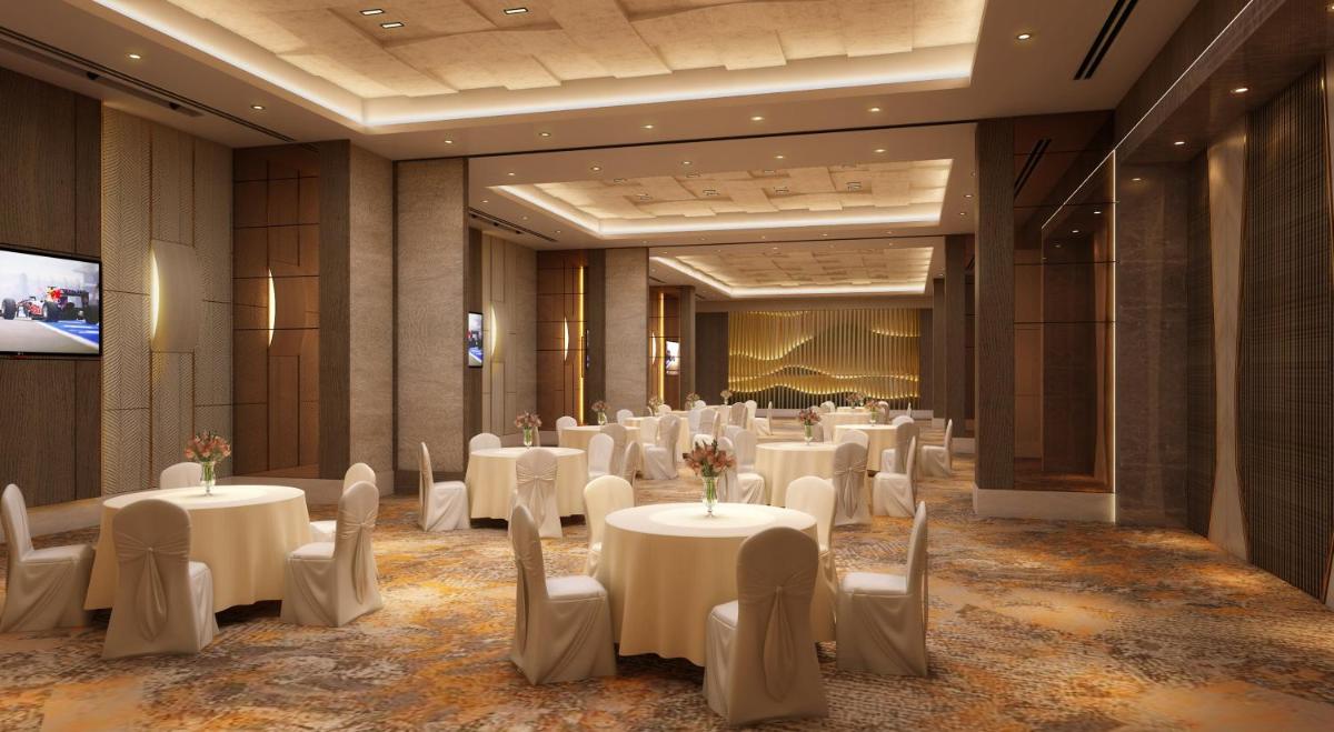 a banquet hall with white tables and chairs and a screen at Holiday Inn Gurugram Sector 90 by IHG in Gurgaon