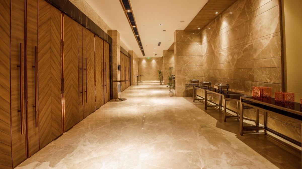 a hallway with wooden walls and a long hallway with tables at Holiday Inn Gurugram Sector 90 by IHG in Gurgaon