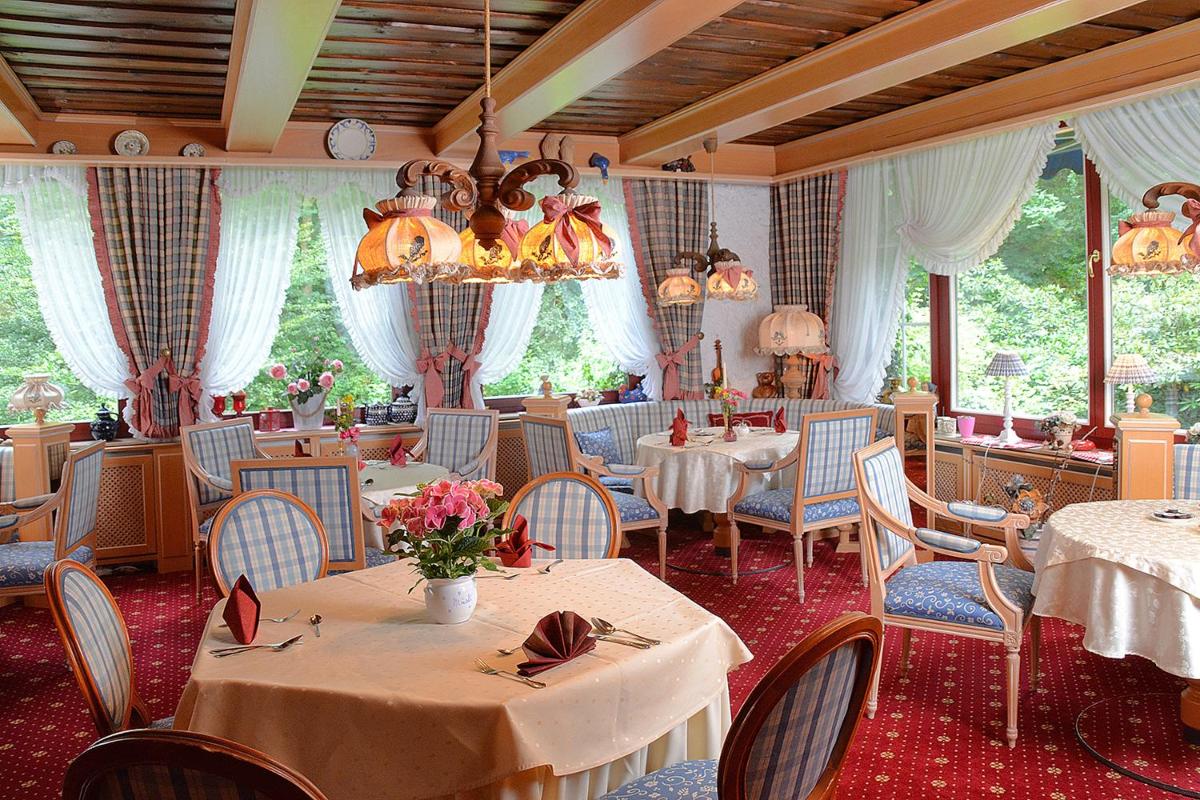 ein Restaurant mit Tischen und Stühlen und einem Kronleuchter in der Unterkunft Wellness und Romantik Hotel Helmboldt in Bad Sachsa