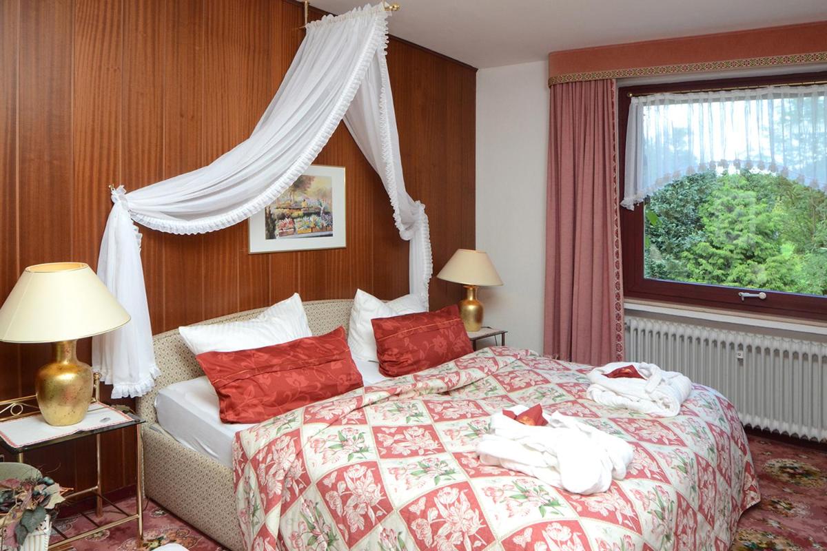 ein Schlafzimmer mit einem Bett mit roten Kissen und einem Fenster in der Unterkunft Wellness und Romantik Hotel Helmboldt in Bad Sachsa + 37 Fotos