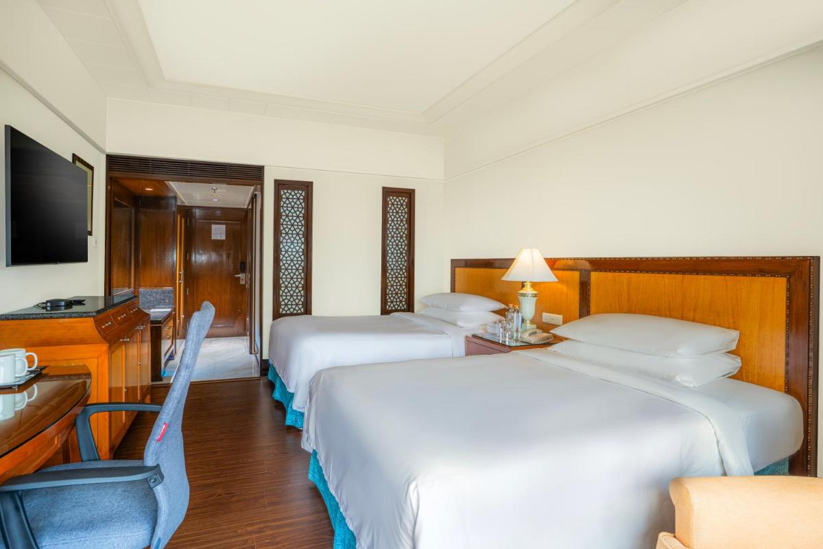 a hotel room with three beds and a television at Hyderabad Marriott Hotel & Convention Centre in Hyderabad