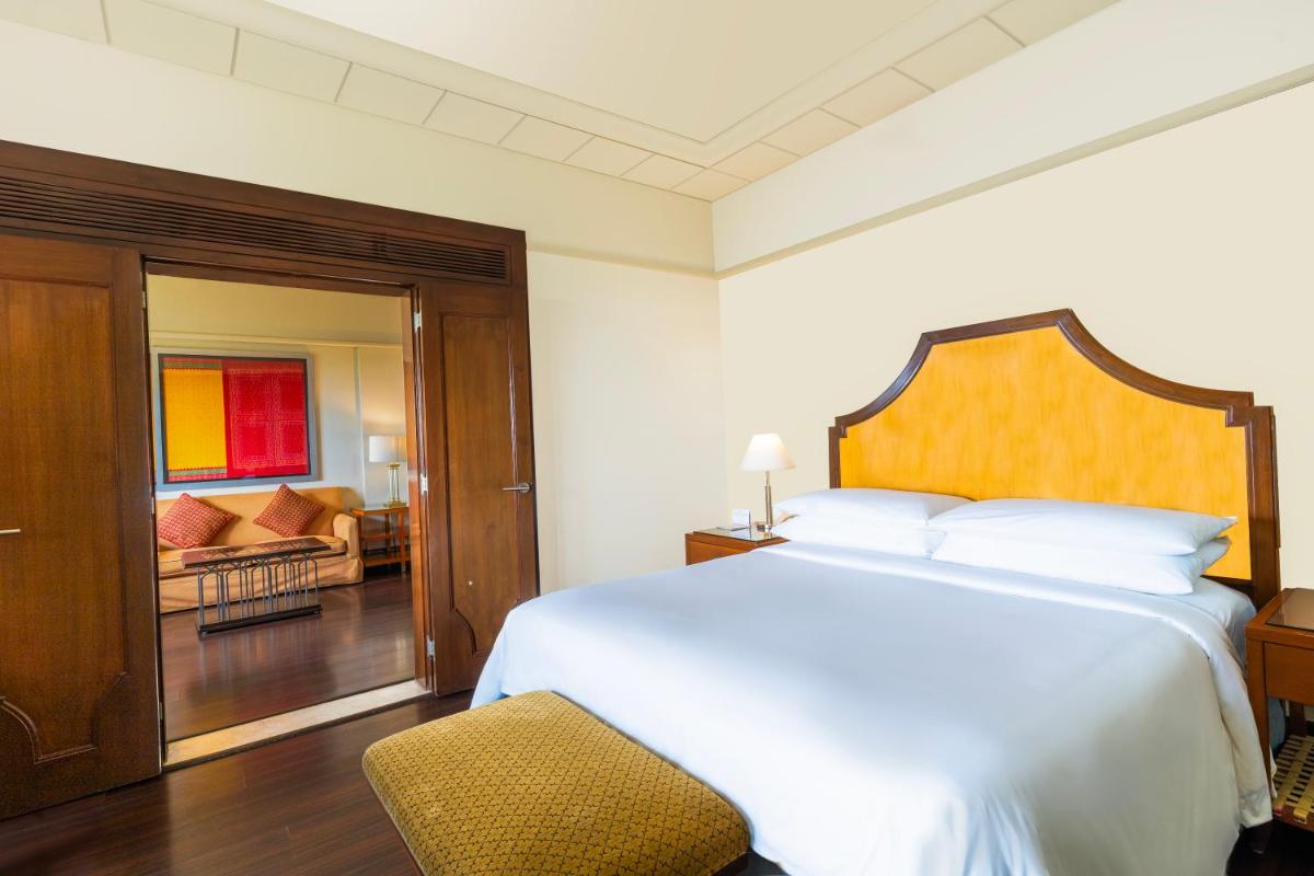 a bedroom with a bed and a chair and a living room at Hyderabad Marriott Hotel & Convention Centre in Hyderabad